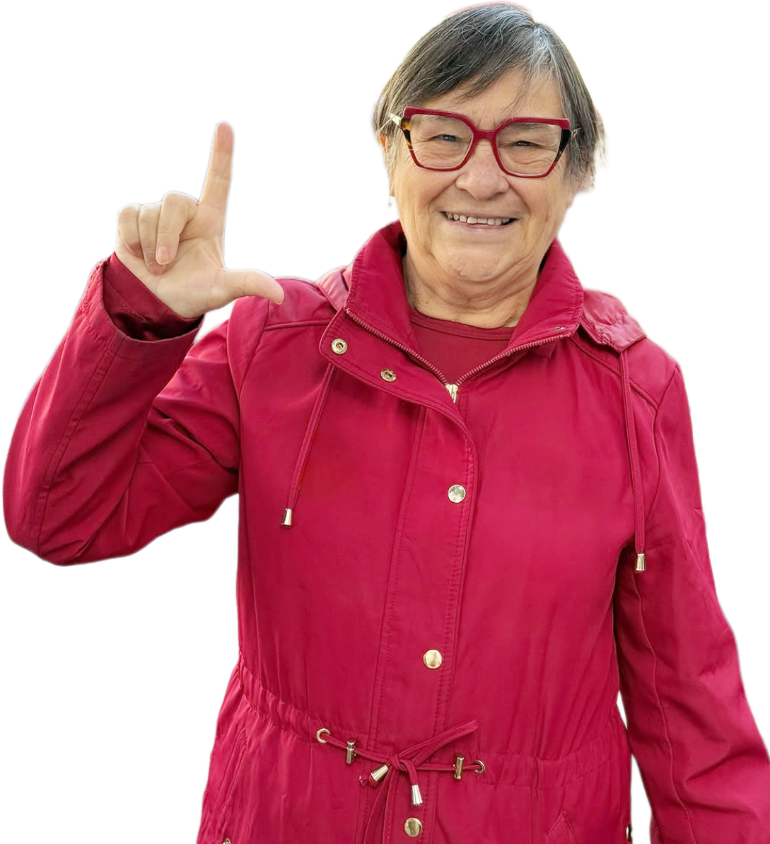 Professora Helenir sorrindo e fazendo o gesto de L